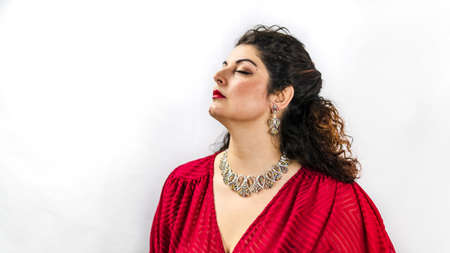 Attractive and elegant white woman in profile with luxurious pendant and gemstone earrings.