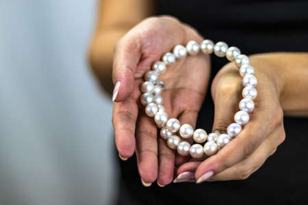 Woman's hands holding precious shiny white natural pearlsの写真素材