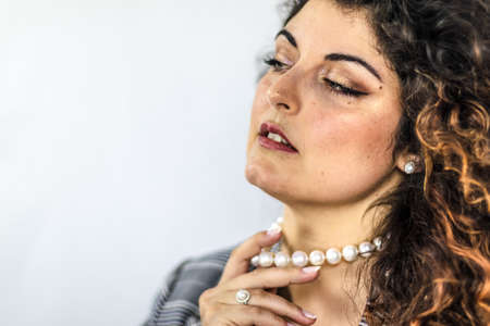 Elegant and attractive woman touches her pearl necklace. Woman with luxurious jewelry made of natural pearls.の写真素材