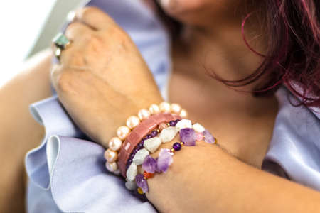 Woman wrist with different gemstone bracelets of various colors and shapes