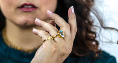 Detail of white woman's hand with luxurious golden rings with precious stones. Topaz and blue sapphire.の写真素材
