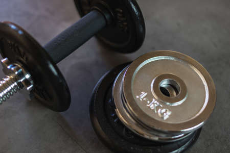 Dumbbell with stacked iron weight plates of different weights and sizes on a concrete surfaceの写真素材