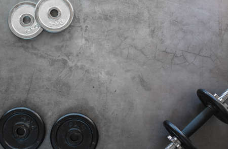 Top view of weight plates and dumbbells on a textured background with empty spaceの写真素材