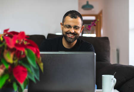 Happy man with his laptop from home with a nice red poinsettiaの写真素材