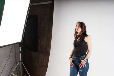 Alternative model with tattoos and jewelry poses in a professional photo studio with spotlightsの写真素材