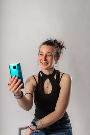 Alternative young woman with tattoos making a video call with her mobile phone.の写真素材