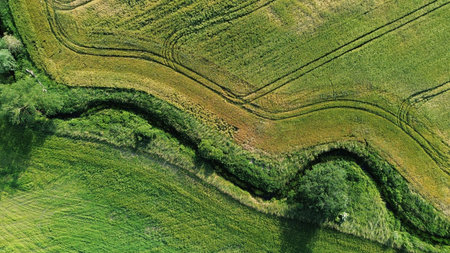Green and brown fields with road and river seen from the top
