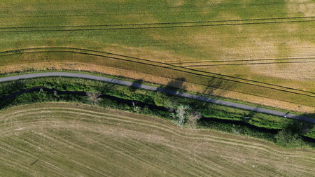 Green and brown fields with road and river seen from the top