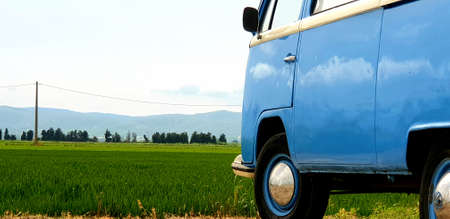 Blue camper van parked in a field with mountains in the backgroundの写真素材