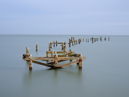 A long exposure on the Swanage Old Pier. I just managed to get a ray of sunlight between clouds to illuminate the pier. The long exposure (30sec) meant that the seagulls are blurry, but I think they make a lively addition to the scenery.の写真素材
