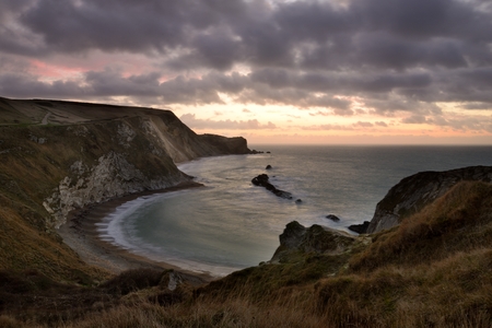 Sunrise by the Man O War bay, Dorset. The dark clouds give a moody feeling to this scene.の写真素材
