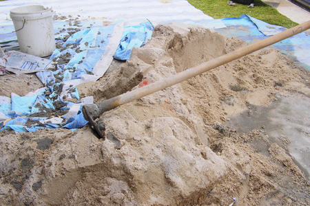 hoe, a white bucket and plastic sheet  on the sand at construction siteの写真素材