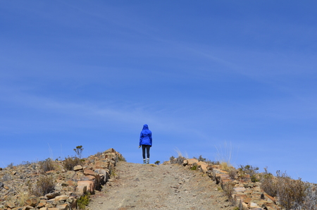 A female hiker on a mountain path, trail, sunny day, Titicaca Lakeの写真素材