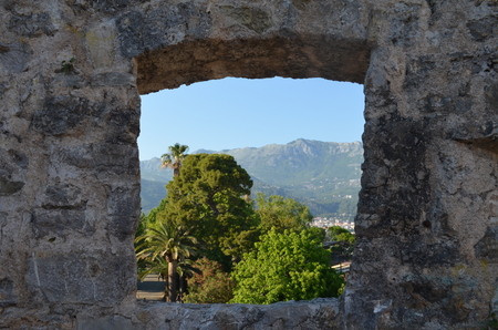 Old stone wall window overlook alley of palm trees. Mountains in the backgroundの写真素材