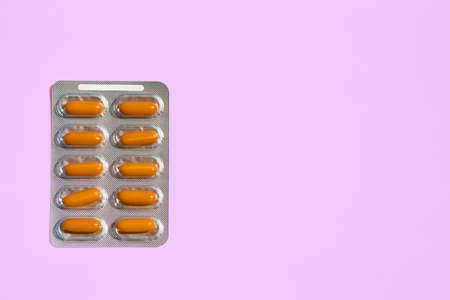 Orange red pills in blisters on a pink background