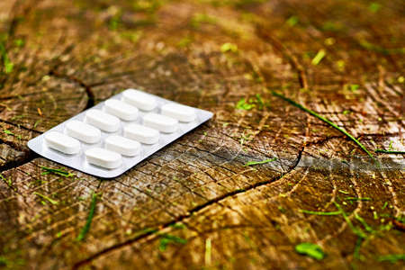 White pills in a blister on a wooden stumpの写真素材