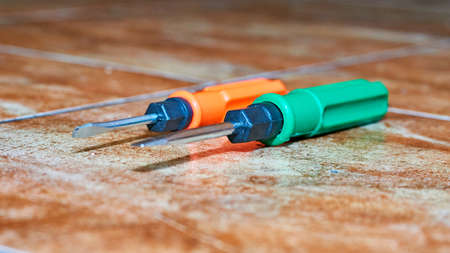 Green and orange screwdrivers on brown marble tilesの写真素材