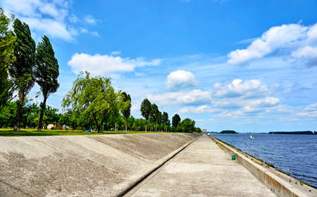 Stone embankment with trees on a warm summer spring dayの写真素材