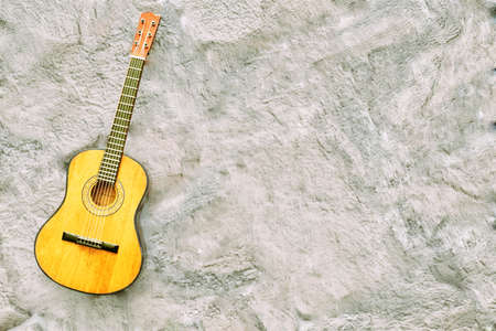 Acoustic yellow guitar on a matte gray pale pink background and space for textの写真素材