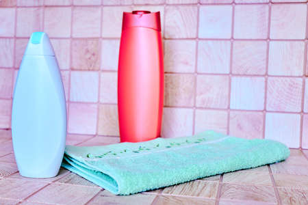 two plastic bottles for detergents and shampoos, a towel on a pink backgroundの写真素材