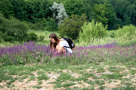 Pretty young woman picking a bouquet of medic herbs. Lilac flowers and greenery