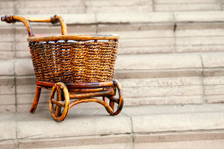 Wooden wicker brown cart on pale gray stepsの写真素材