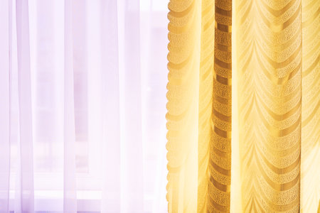 Golden beown curtains and purple tulle on the window in the warm midday sunの写真素材