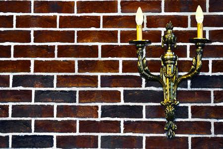 Double gold candlestick lamp on red black brick wallの写真素材