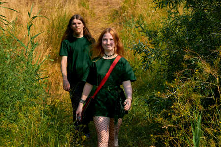 Young cheerful couple guy and girl in green clothes are walking in sunny forest