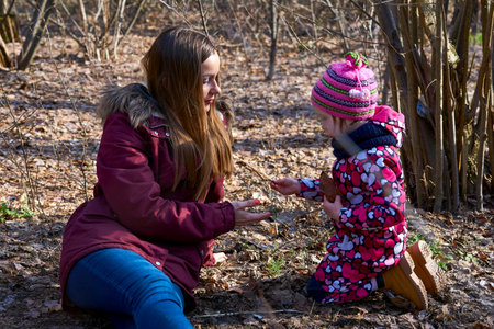 A young mother tells the child about nature in the spring autumn forest