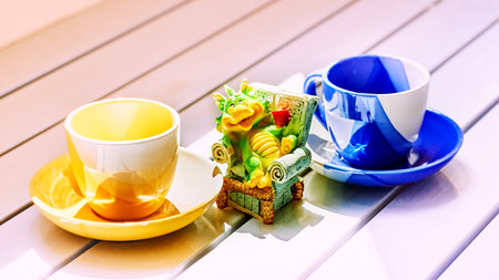 Little green crocodile imp drinks coffee tea and two colored cupsの写真素材