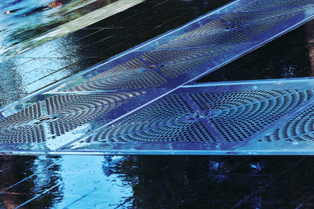 Wet tiled pavement floor with sewer metal gratings for water drainage