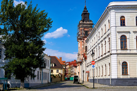 A small light pedestrian street of a medieval city with a church bell tower