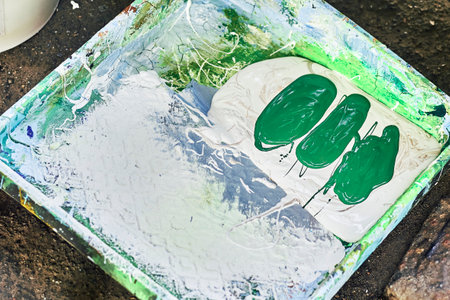 Painter craftsman artist tray at workplace with green and white paint