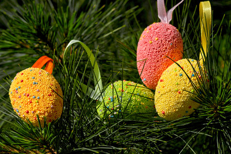 Light multi colored festive Easter eggs on fir branches in sunny spring day