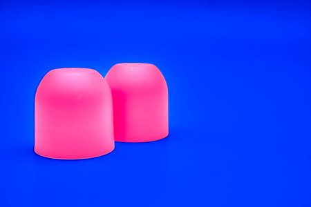 Pink magenta caps cones cylinders and place for text on dark blueの写真素材