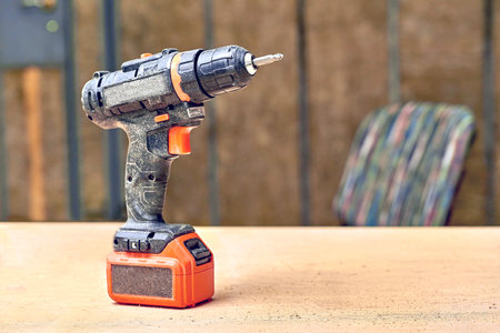 Electric drill,screwdriver on a plywood wooden surface with sawdust in workshopの写真素材