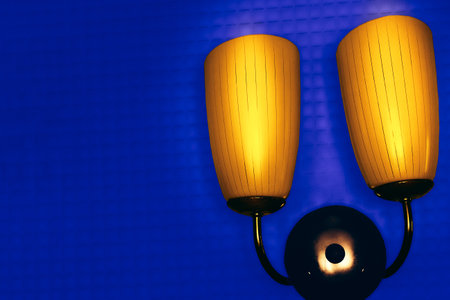 Bright yellow home double lamp lantern on a dark blue checkered wall surfaceの写真素材