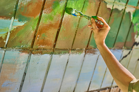 Female artist's hand with a brush painting on the wall with different colorsの写真素材