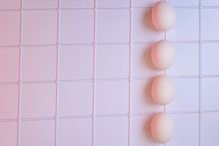 Four fresh chicken eggs on a plastic checkered shelf in pink in refrigeratorの写真素材