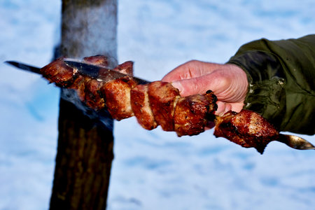 Knife test of steaming grilled meat on a skewer for readiness for eatingの写真素材