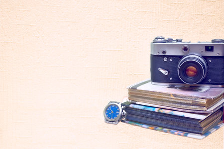 Old vintage film photo camera with photo album and watch isolated on pale pink