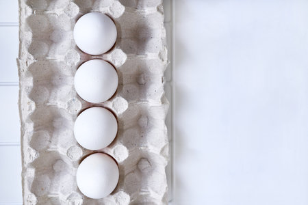 Four fresh chicken eggs on a plastic checkered shelf in package in refrigerator