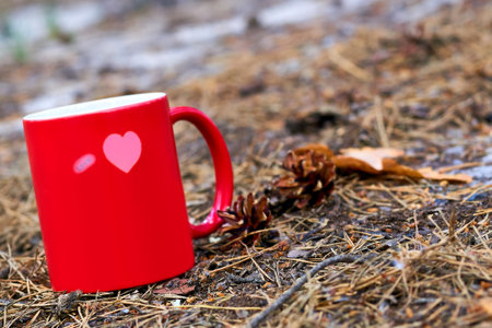 Red ceramic cup inscription love with hot drink beverage,autumn grassの写真素材
