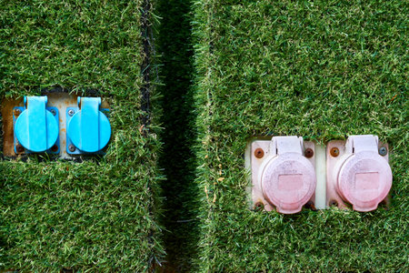 Electric sockets for charging on a pole with artificial green grass in the park