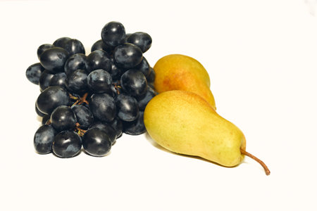 Dainty dessert. Yellow ripe sweet pears,bunch of black grapesの写真素材