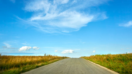 Traveling by car. Asphalt road among summer fields,blue skyの写真素材
