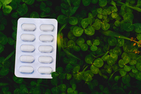 White pills in plastic blister on green clover grass on meadow