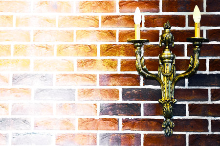 Double gold candlestick lamp on red black brick wallの写真素材