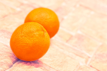Two ripe sweet juicy oranges on light brown cobblestone